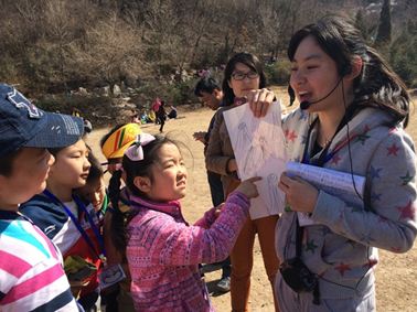 孩子們合作扮演大樹從生根、發芽、長葉、開花的一生后，聽志愿者講解愛護林木的重要性